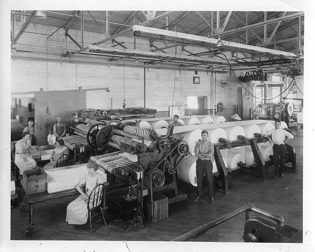 Male and female employees by paper pressing machinery