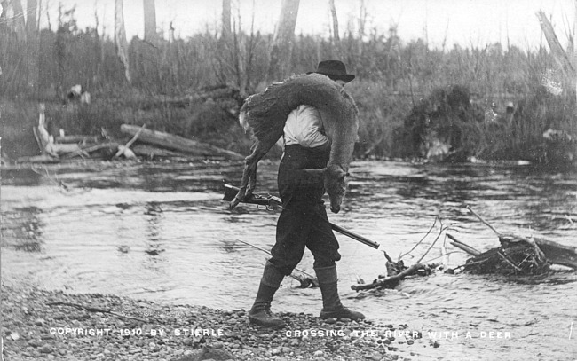 Hunter crossing river with a deer