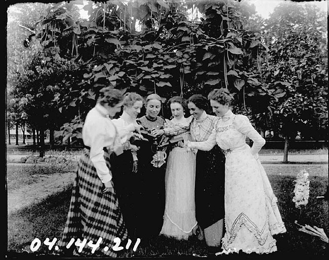 Six Young Women Pouring Beverages into One Cup