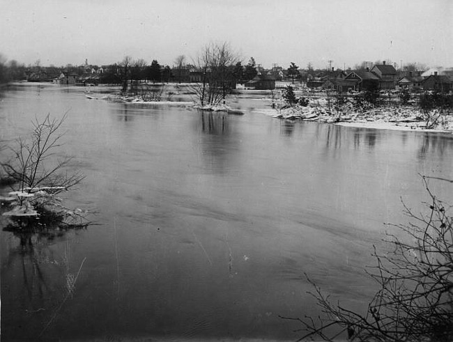 Island in flooded river with homes in background, Lansing, 1904