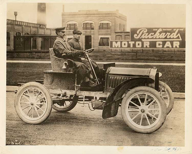 1904 Packard Model L with driver & passenger in front of Packard Motor Car Co.