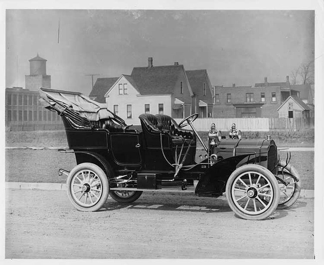 1906 Packard 24 Model S on street with houses and brick buildings in background