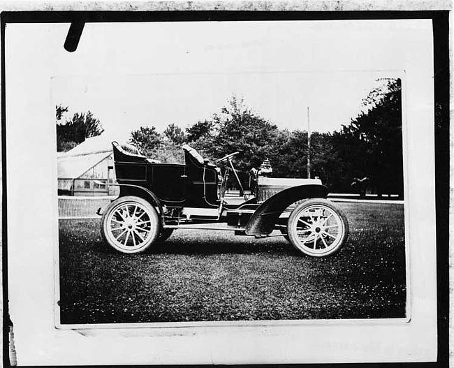 1906 Packard parked on grass with greenhouse in background