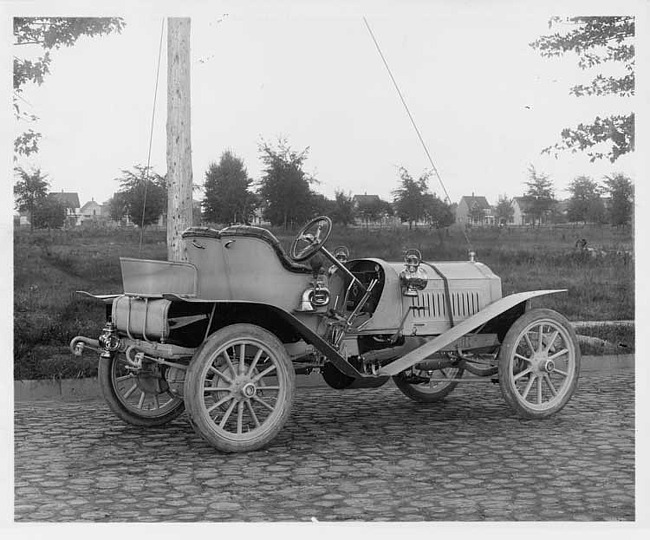 1907 Packard 30 Model U light colored runabout on cobblestone road