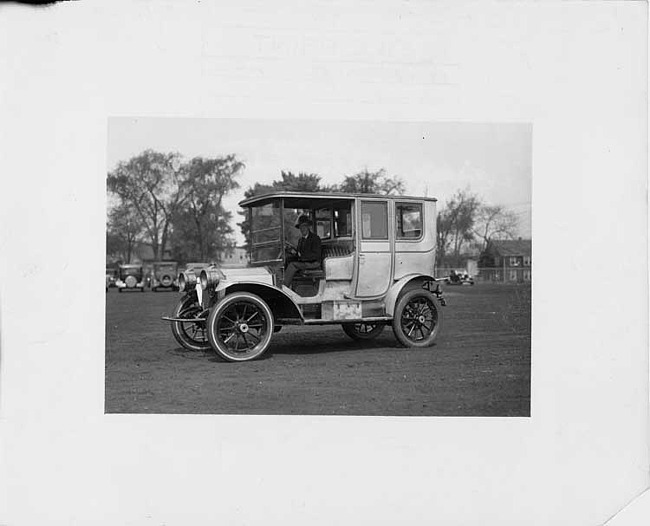 1909 Packard 30 Model UB limousine on lawn with male chauffeur