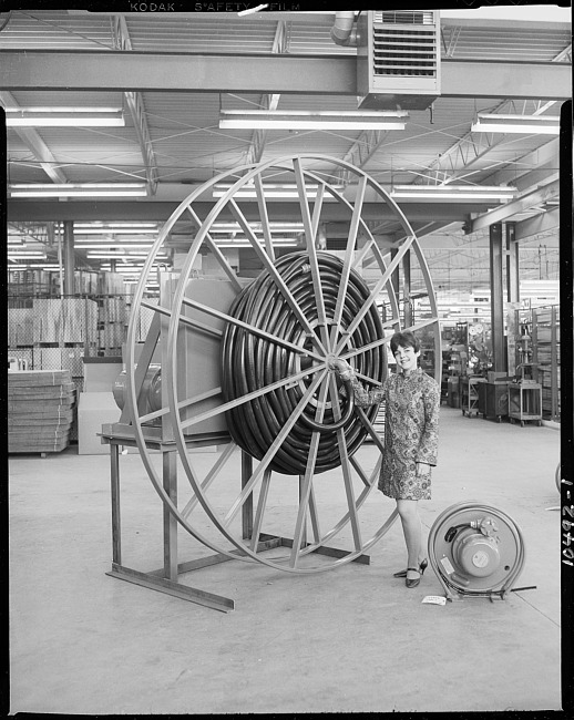 Woman standing by large hose reel in warehouse