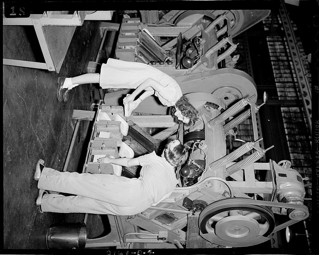 Two women examining paper company machine