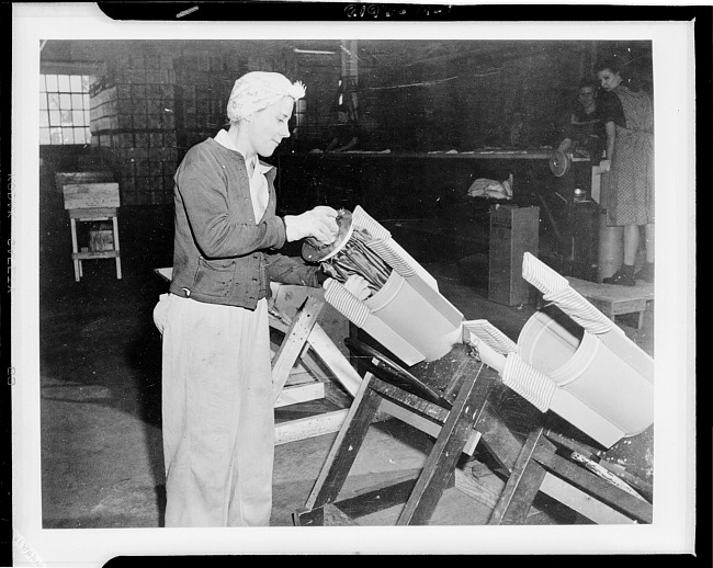 Woman worker packing parachute into cylinder