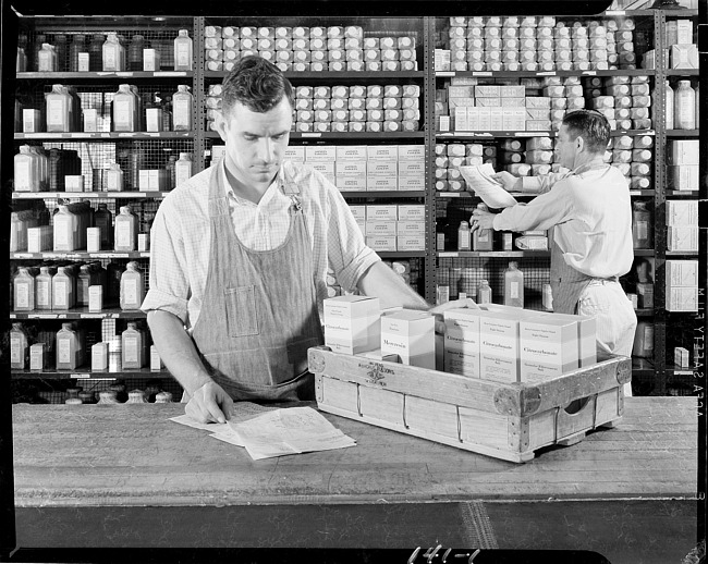 Two men pulling pharmaceuticals from stocking shelves