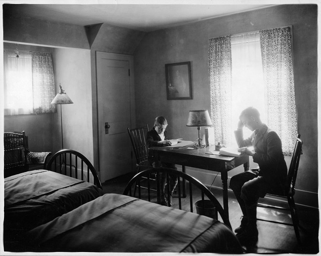 Two boys reading in bedroom, photograph