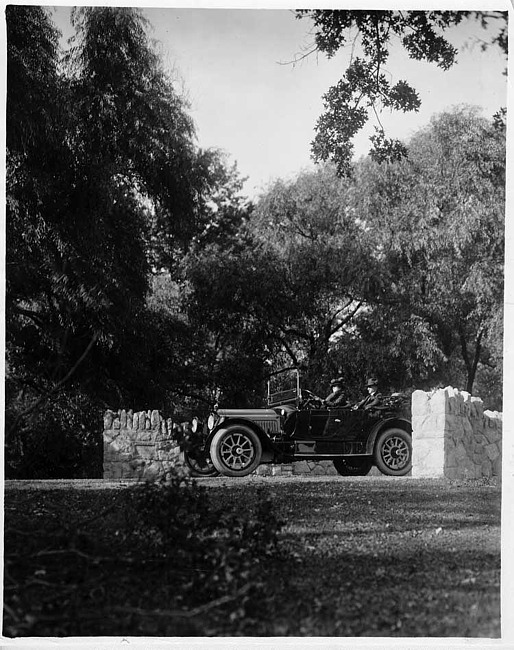 1917 Packard 2-25 4-person cloverleaf type runabout on road between stone walls