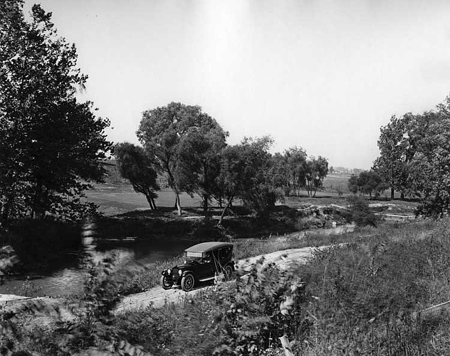 1918 Packard phaeton, top raised, male driver and passenger, in distance on country road