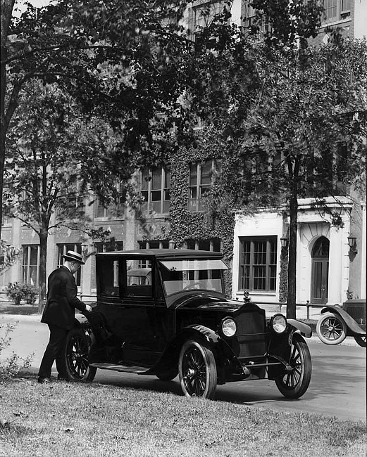 1921-1922 Packard coupe parked on street across from Packard plant