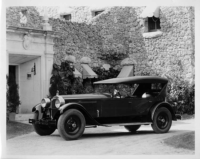 1925 Packard touring car, seven-eights left front view, parked in front of large home, top raised