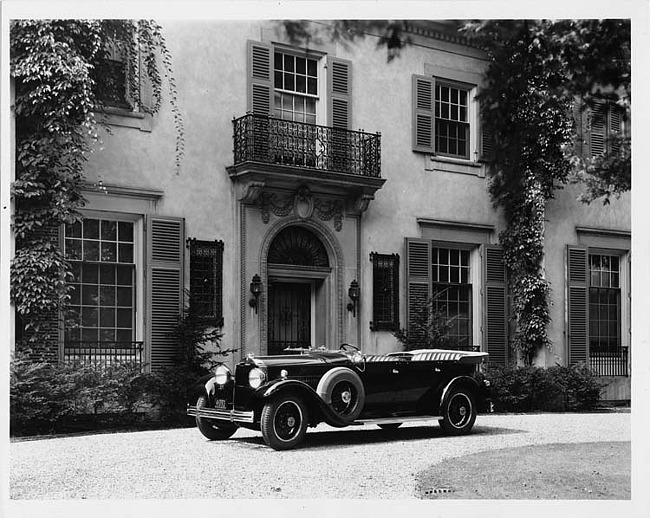 1930 Packard touring car, three-quarter left side view, top folded, parked on drive in front of house