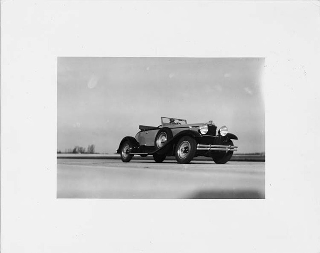 1930 Packard roadster, three-quarter left front view, top folded, male driver, coming around corner