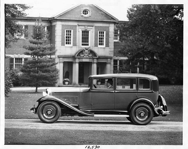 1932 Packard sedan, left side view, parked on drive in front of house, male driver