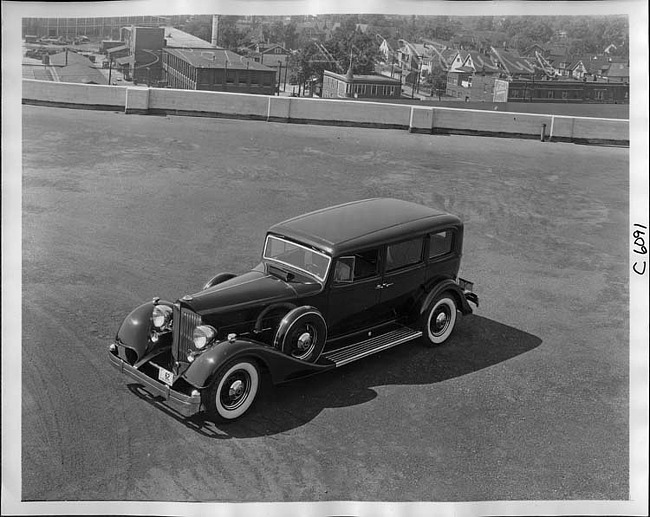 1934 Packard sedan, three-quarter left elevation view, houses in background