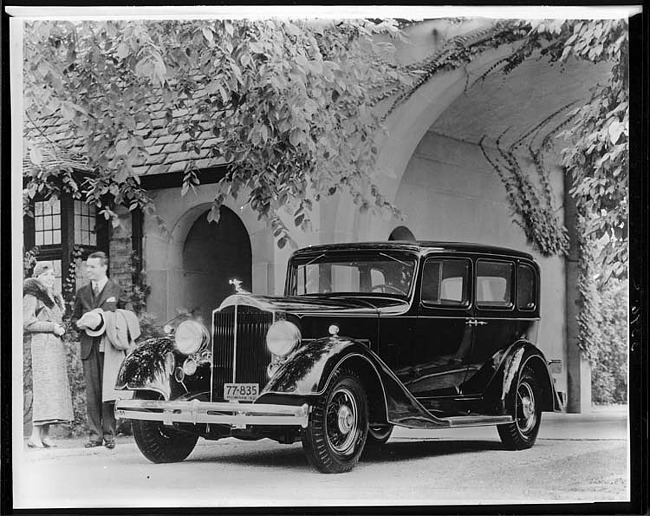 1934 Packard sedan, three-quarter front left view, couple standing at front right side