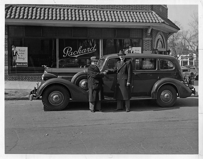 1936 Packard limousine parked on street in front of Packard dealership