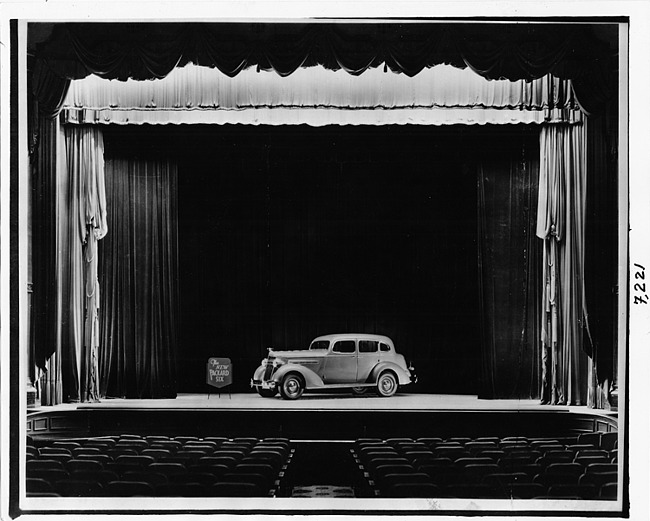 1937 Packard touring sedan, nine-tenths left side view, displayed on stage