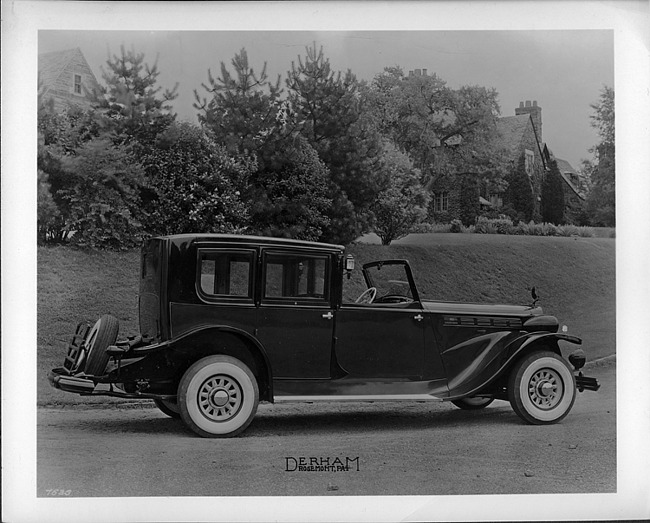 1937 Packard glass panel brougham, parked on road, house in background