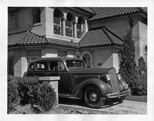 1937 Packard touring sedan, three-quarter front view, parked in driveway of home