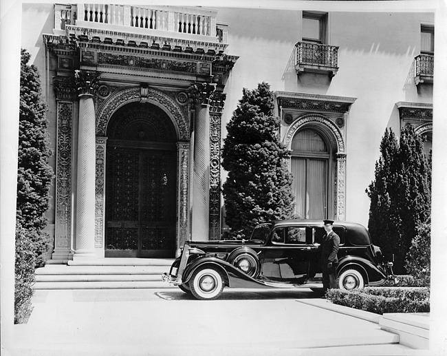 1937 Packard formal sedan, parked in driveway in front of house with chauffeur