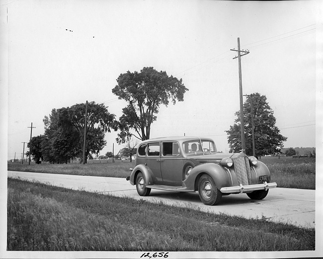 1938 Packard touring sedan, seven-eights front view, on drive, male driver