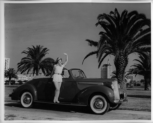 1939 Packard convertible coupe, female standing on running board waving
