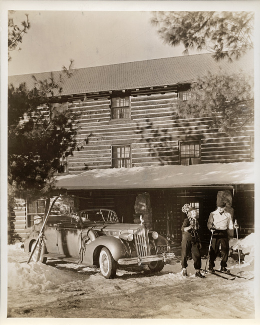 1939 Packard convertible sedan, top folded, couple in ski gear, ski lodge in background