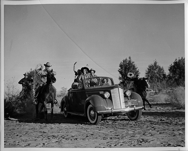 1939 Packard convertible coupe with cowgirls, three cowboys on horseback approaching