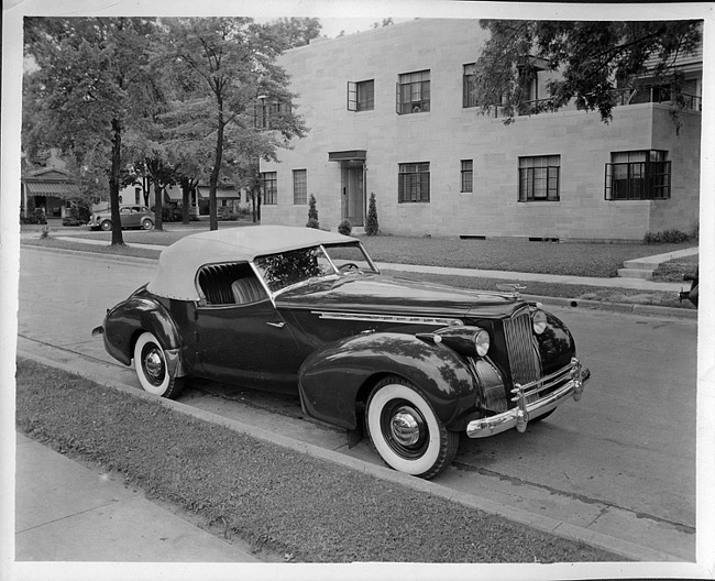 1940 Packard convertible victoria, three-quarter right front view, top raised, parked on street