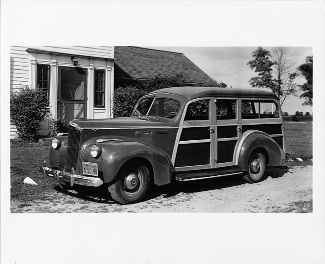 1941 Packard station wagon, three-quarter left side view, parked in driveway in front of house