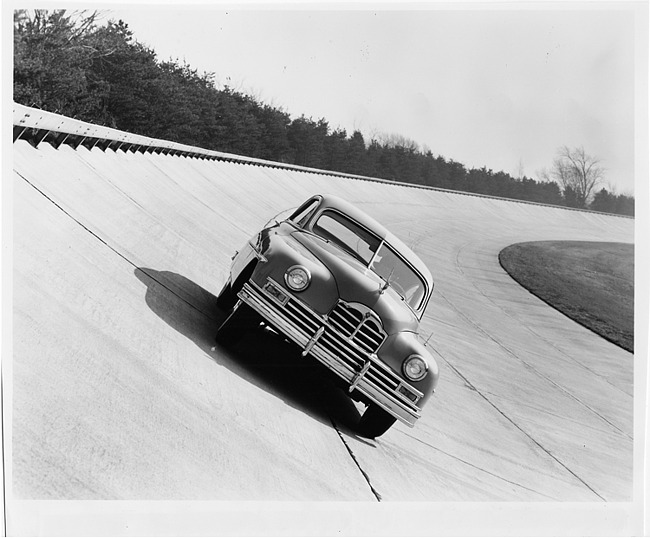 1949 Packard sedan, front view, rounding track at Packard Proving Grounds