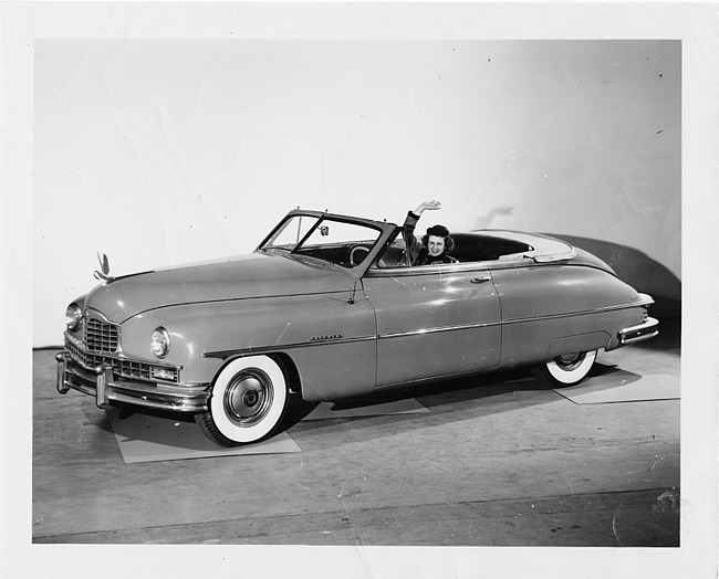 1950 Packard custom convertible, top folded, female behind wheel waving