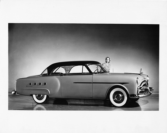 1951 Packard Mayfair, nine-tenths right side view, female standing by driver's door