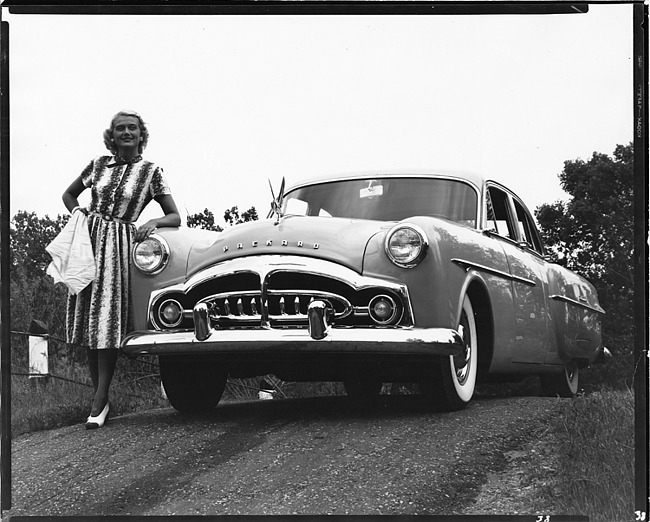 1951 Packard 300 sedan, front view, parked on hill, female leaning on front left side