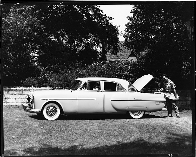 1951 Packard 300 sedan, parked on grass, man putting golf clubs into trunk