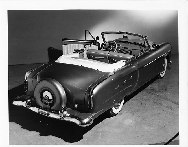 1952 Packard convertible, three-quarter rear view, top folded, interior visible, driver's door open