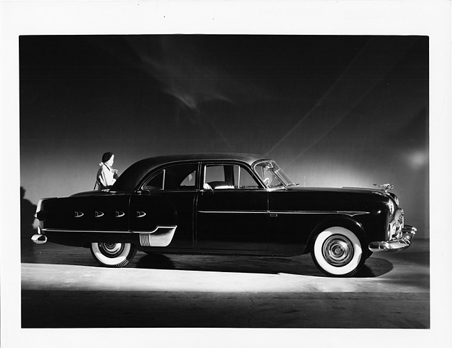 1952 Packard 400 Patrician, nine-tenths right side view, female standing at rear driver's side