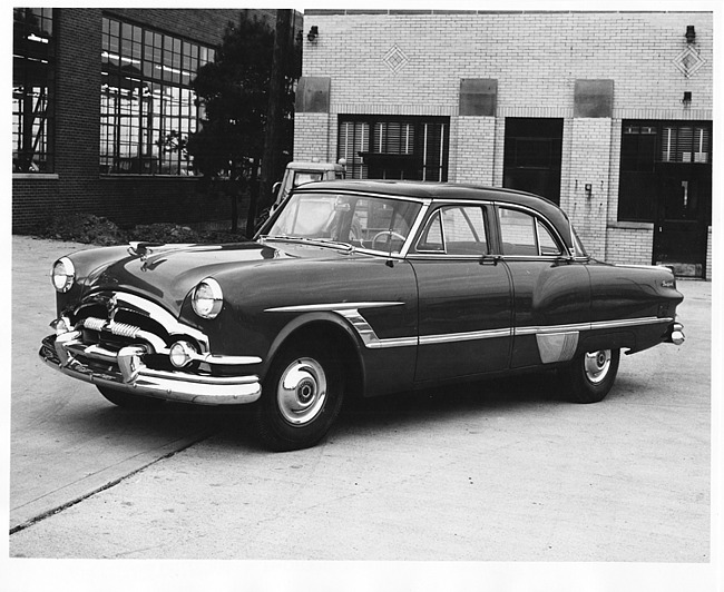 1953 Packard 4-door sedan, seven-eights left side view, parked in drive near brick building