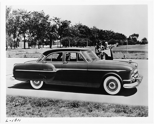 1953 Packard deluxe Clipper, two men standing near driver's door looking at map for directions