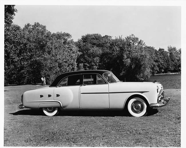 1952 Packard touring sedan, right side view, parked on grass, couple in background