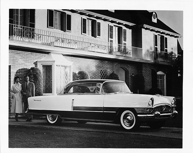 1955 Packard 400 hardtop, parked in driveway of home, couple standing at rear of car