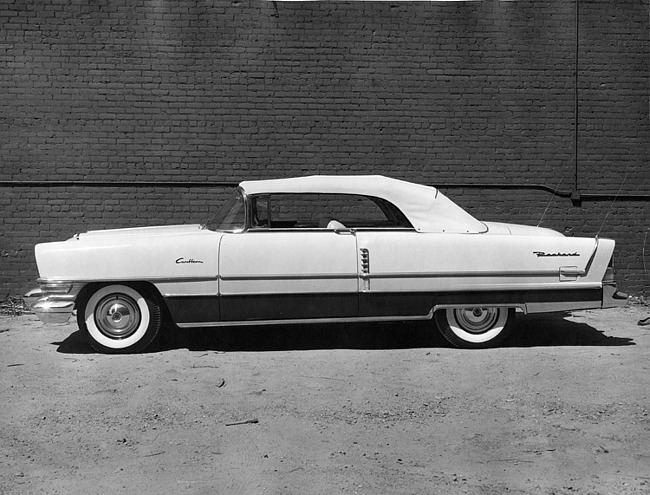 1955 Packard convertible, left side view, top raised, parked next to brick wall