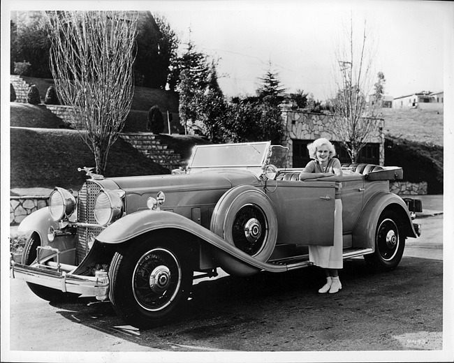 1932 Packard sport phaeton and owner actress Jean Harlow leaning on open driver's door