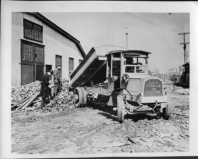 1917 Packard dump truck dumping out a load of bricks