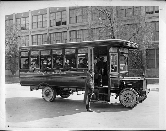 1917 Packard jitney bus full of male passengers, parked on street