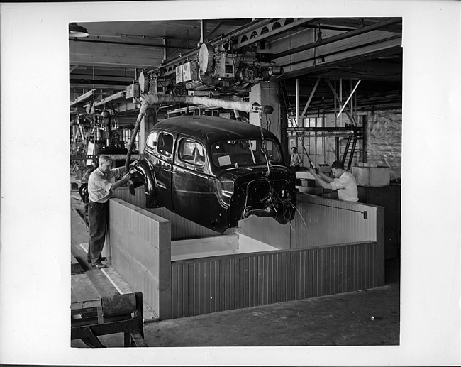 Packard factory assembly line, body dropping from above, worker on either side